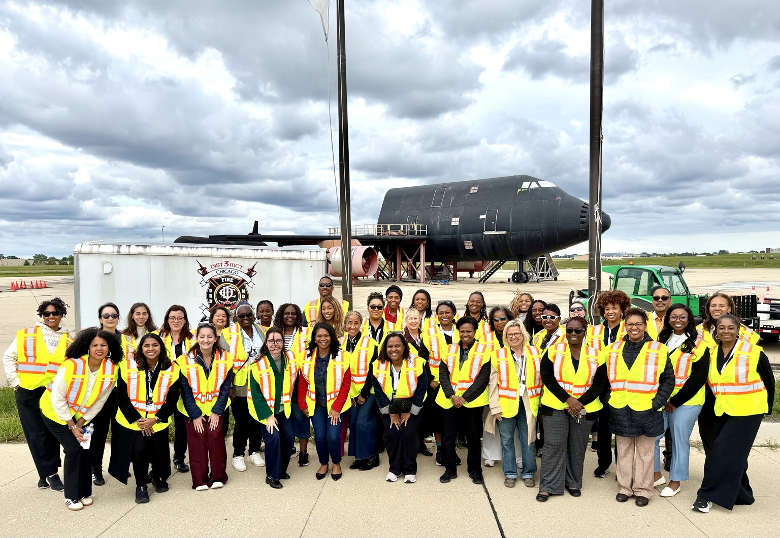 Group wearing safety vests beside an aircraft training structure