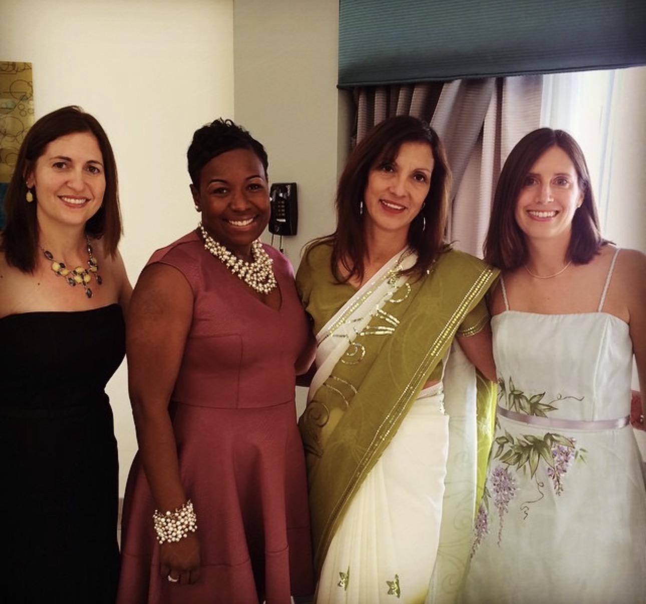 Four women posing together in colorful formal attire